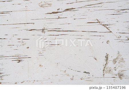An old weathered wooden surface that has been painted white. Cracks and scratches, chips exposed the texture of the wood, there are also stains, drips, dents. Abstract background blank template 135487196