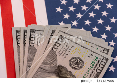 Stack of US dollar banknotes on the United States flag Stack of US dollar banknotes on the United States flag 135487900