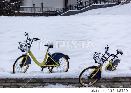 Two bicycles covered with snow while snowing in winter 135488530