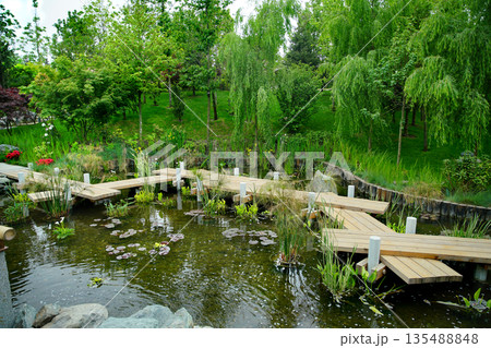 Wooden zigzag Japanese bridge in Japanese garden in Krasnodar Wooden zigzag Japanese bridge in Japanese garden in Krasnodar 135488848