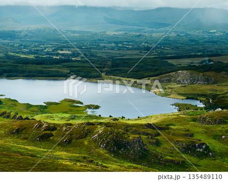 Viewing peaceful Lough and green countryside from rocky hillside during daytime. Viewing peaceful Lough and green countryside from rocky hillside during daytime. 135489110