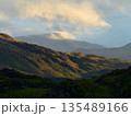A scenic mountain landscape bathed in golden sunlight. 135489166