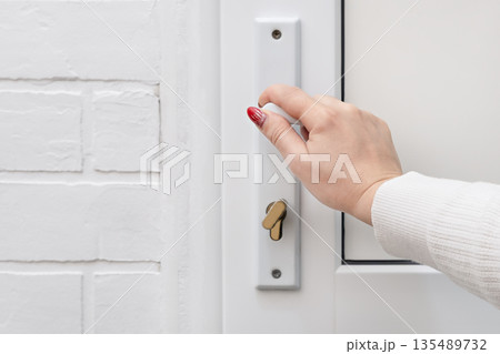 A woman's hand opens a white door 135489732