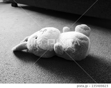 Plush Bunny Toy Lying on Floor Black White. Cute stuffed bunny rabbit plush toy fallen on carpet floor, black and white moody shot. Childhood nostalgia concept. Plush Bunny Toy Lying on Floor Black White. Cute stuffed bunny rabbit plush toy fallen on carpet floor, black and white moody shot. Childhood nostalgia concept. 135489823