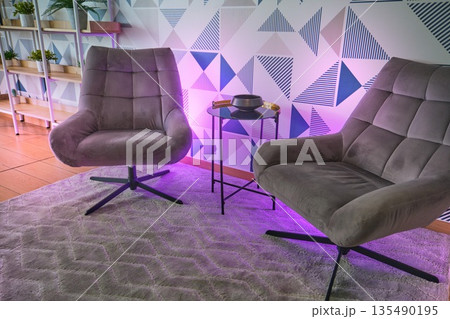 Modern armchairs illuminated by purple ambient lighting 135490195