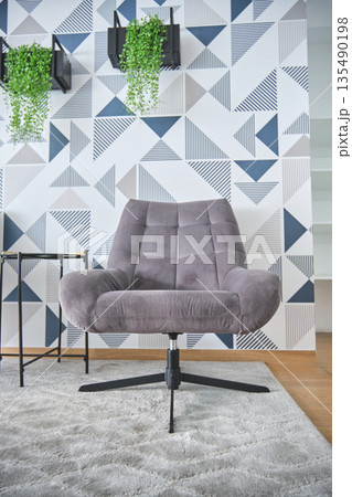 Modern living room interior with grey armchair and geometric wallpaper 135490198