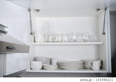 White kitchen cabinet storing clean crockery and glassware 135490221