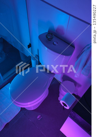 Modern bathroom toilet illuminated with blue and purple neon lighting 135490227