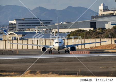 夕方の大阪空港（伊丹空港）　タキシング中の飛行機　大阪府豊中市 135491732