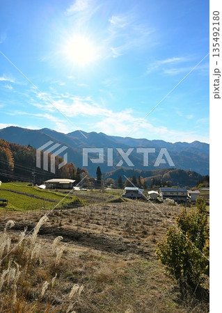 秋の山並みと草地が広がる紅葉風景（長野県長野市） 135492180