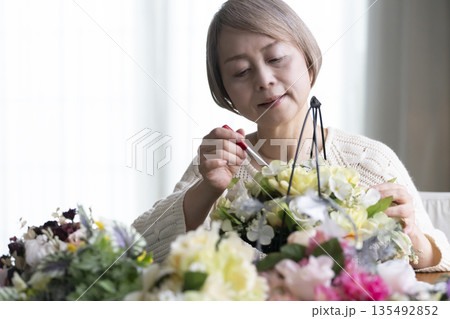 リビングで趣味のフラワーアレンジメントをするシニア女性 自然光 リビングで趣味のフラワーアレンジメントをするシニア女性 自然光 135492852