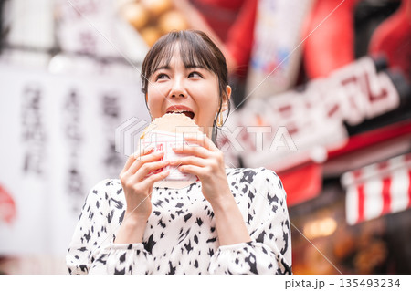 大阪名物たこせんを食べている女性 135493234