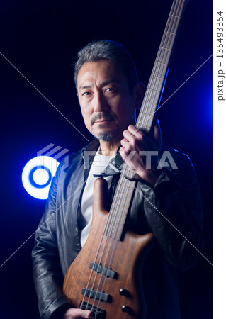 ライブハウスのステージでベースを演奏するバンドマンの中高年男性 ライブハウスのステージでベースを演奏するバンドマンの中高年男性 135493354