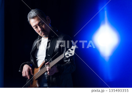 ライブハウスのステージでベースを演奏するバンドマンの中高年男性 135493355