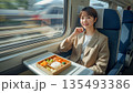 新幹線で駅弁を食べる女性 135493386