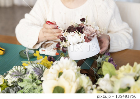リビングで趣味のフラワーアレンジメントをするシニア女性の手元 リビングで趣味のフラワーアレンジメントをするシニア女性の手元 135493756