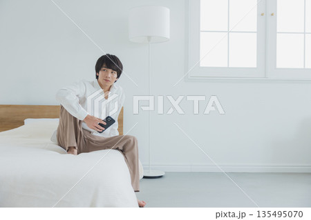 ベッドでスマホを見る男性　  135495070