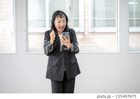 スマホを見て喜ぶビジネスウーマン スマホを見て喜ぶビジネスウーマン 135497675