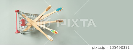 Eco-friendly bamboo toothbrushes in small shopping cart on light background 135498351