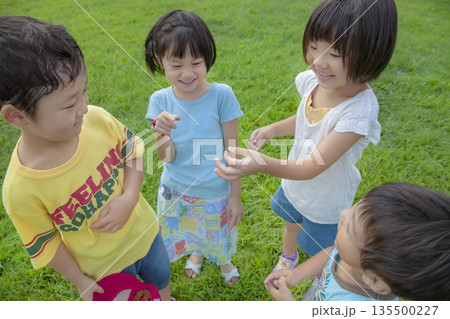 公園で捕まえたバッタを見る子供たち 公園で捕まえたバッタを見る子供たち 135500227