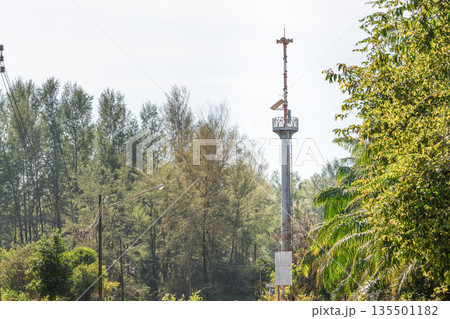 A tower with a tsunami or emergency warning system in the coastal area in Thailand. An observation deck loudspeakers in middle of the trees to monitor. Public safety and informing the public about A tower with a tsunami or emergency warning system in the coastal area in Thailand. An observation deck loudspeakers in middle of the trees to monitor. Public safety and informing the public about 135501182