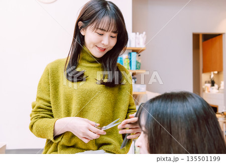 髪をカットする女性美容師　美容室 135501199