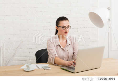Middle-aged business woman in office. Female using laptop computer at workplace, typing document, copy space 135501694