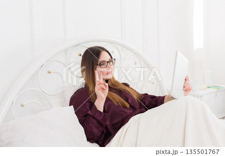 Sunday morning in bed. Young woman making selfie for social networks in bed. Communication, internet addiction concept 135501767