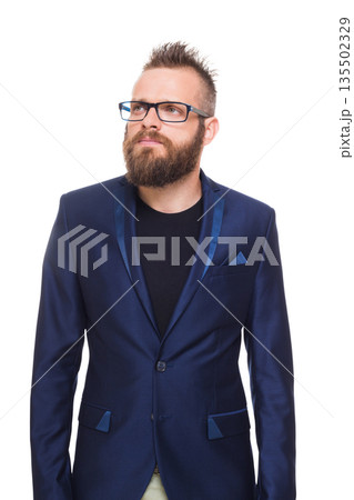 Young bearded man isolated at white background. Portrait of a confident stylish guy in eyeglasses looking at camera. Boy style, trendy hipster with cool hairstyle in blue suit. 135502329