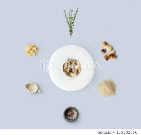 Risotto with wild mushrooms ingredients flat lay, isolated on blue background. Rice, fungus, sauce, parmesan and other ingredients around plate with dish ready 135502350