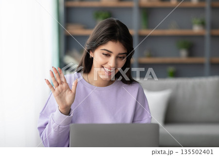 Online Meeting. Happy young woman using laptop computer for virtual conferencing, having video call at home. Cheerful millennial female communicating with colleagues, friends or psychologist remotely Online Meeting. Happy young woman using laptop computer for virtual conferencing, having video call at home. Cheerful millennial female communicating with colleagues, friends or psychologist remotely 135502401