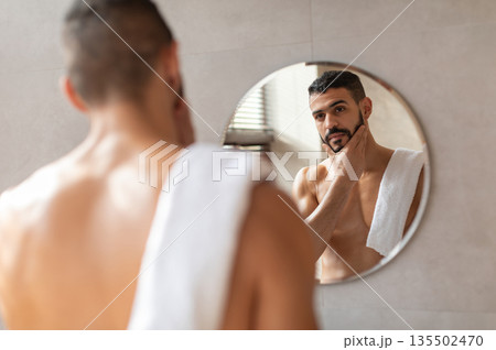 Male Facial Care. Portrait Of Handsome Arab Man Looking At His Reflection In Mirror In Bathroom And Touching Beard, Attractive Masculine Middle Eastern Guy Enjoying His Appearance, Selective Focus Male Facial Care. Portrait Of Handsome Arab Man Looking At His Reflection In Mirror In Bathroom And Touching Beard, Attractive Masculine Middle Eastern Guy Enjoying His Appearance, Selective Focus 135502470