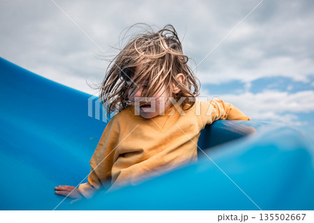 little child in yellow sweatshirt sliding down against sky little child in yellow sweatshirt sliding down against sky 135502667
