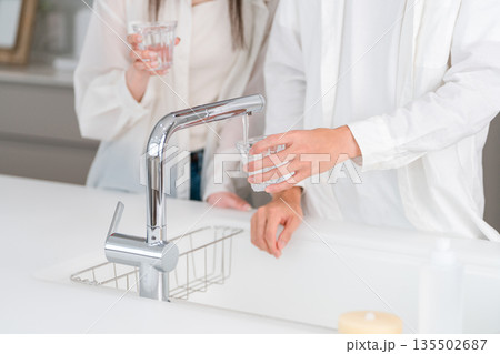 キッチンの蛇口から水道水をコップに注ぐ男性の手元 キッチンの蛇口から水道水をコップに注ぐ男性の手元 135502687