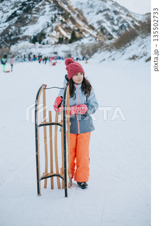 little girl walking on a snow with wooden sled in her hands little girl walking on a snow with wooden sled in her hands 135502733