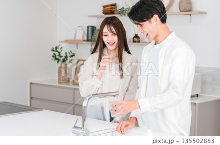 キッチンで水を飲む笑顔のカップル,夫婦（浄水器,水道水） 135502883
