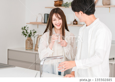 キッチンで水を飲む笑顔のカップル,夫婦(浄水器,水道水) キッチンで水を飲む笑顔のカップル,夫婦(浄水器,水道水) 135502885
