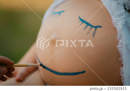 Pregnant woman belly closeup with smiling funny face drawing Pregnant woman belly closeup with smiling funny face drawing 135502915