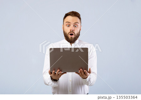 Shocked young businessman in formal wear looking at laptop screen in disbelief on grey studio background. Stunned office worker learning unbelievable news online, learning about huge sale Shocked young businessman in formal wear looking at laptop screen in disbelief on grey studio background. Stunned office worker learning unbelievable news online, learning about huge sale 135503364