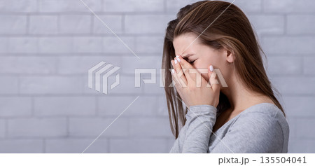 Desperate young woman crying from hopelessness, covering her face with hands, blank space. Depressed millennial lady suffering from PTSD, stress or anxiety. Mental health concept 135504041