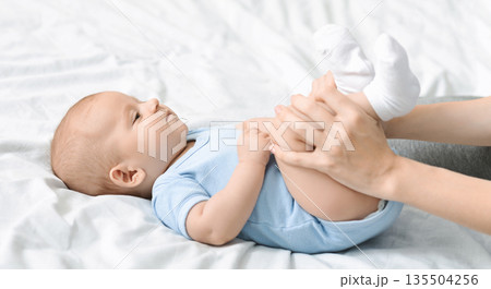 Constipation in babies. Mom doing gymnastics with her newborn child to relieve gas, panorama Constipation in babies. Mom doing gymnastics with her newborn child to relieve gas, panorama 135504256
