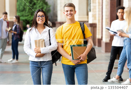 Happy diverse students having break in university campus, smiling to camera Happy diverse students having break in university campus, smiling to camera 135504407