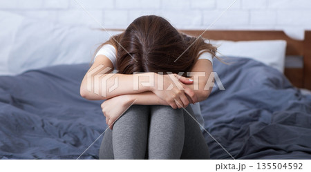 Stressed young woman having negative emotions, feeling depressed and crying on bed. Lonely millennial lady suffering from sleep deprivation, loneliness or anxiety. Mental health concept Stressed young woman having negative emotions, feeling depressed and crying on bed. Lonely millennial lady suffering from sleep deprivation, loneliness or anxiety. Mental health concept 135504592
