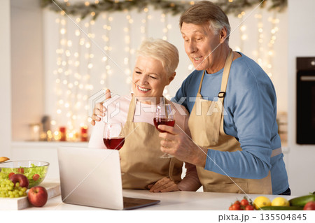 Happy Aged Couple Making Video Call On Laptop Celebrating Christmas Toasting And Drinking Wine In Kitchen At Home. Xmas And New Year Holidays Celebration During Coronavirus Pandemic Quarantine Happy Aged Couple Making Video Call On Laptop Celebrating Christmas Toasting And Drinking Wine In Kitchen At Home. Xmas And New Year Holidays Celebration During Coronavirus Pandemic Quarantine 135504845