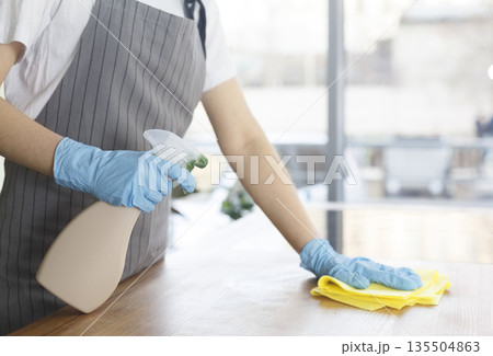 Closeup of female hands in rubber gloves cleaning the table before work on kitchen, eco quarantine cleaning 135504863