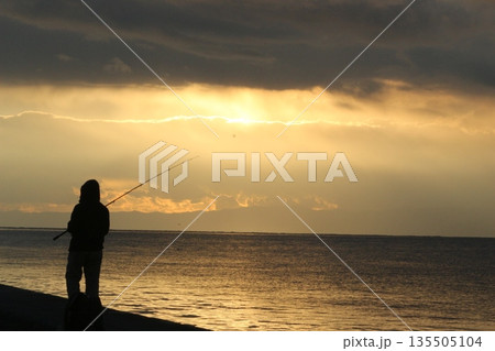 海に沈む夕日と釣り人 135505104
