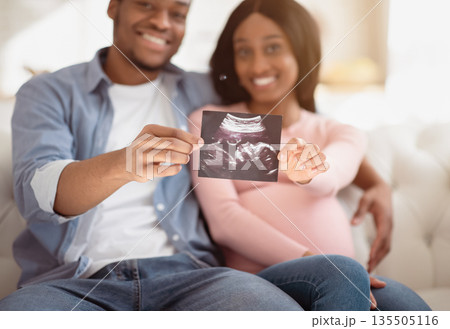 Young future parents holding photo of their unborn baby at home, selective focus on hands. Positive expectant couple with sonogram of their child, creating happy memories together Young future parents holding photo of their unborn baby at home, selective focus on hands. Positive expectant couple with sonogram of their child, creating happy memories together 135505116