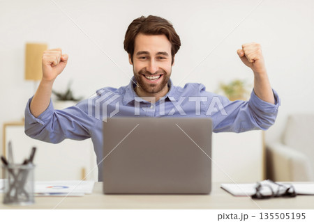 Joyful Businessman At Laptop Shaking Fists And Shouting Celebrating Business Success Looking At Computer Screen Sitting At Desk In Modern Office. Victory Celebration, Successful Career, Great News 135505195