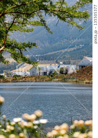 Lake in front of modern houses with mountains and vineyards in background Lake in front of modern houses with mountains and vineyards in background 135505377