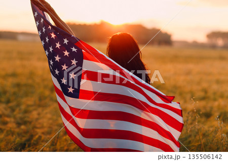 Patriotic Independence day and 4th of July Woman farmer in the agricultural field with american flag on sunset. Patriotic Independence day and 4th of July Woman farmer in the agricultural field with american flag on sunset. 135506142
